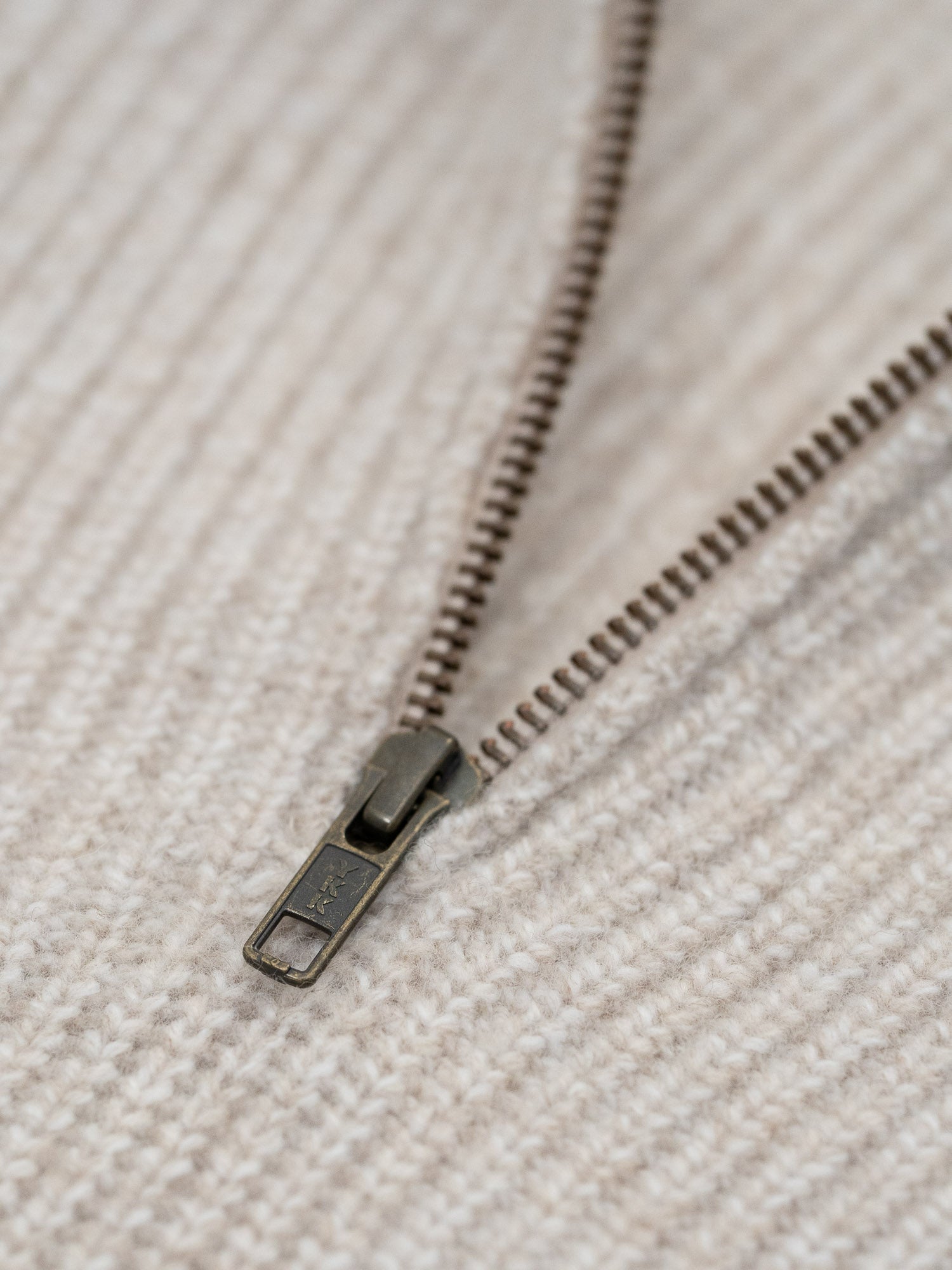 Detailansicht eines nachhaltigen und fairen Troyer aus 100% Merinowolle in beigemeliert von FUXBAU mit einem hochwertigm YKK Zipper.